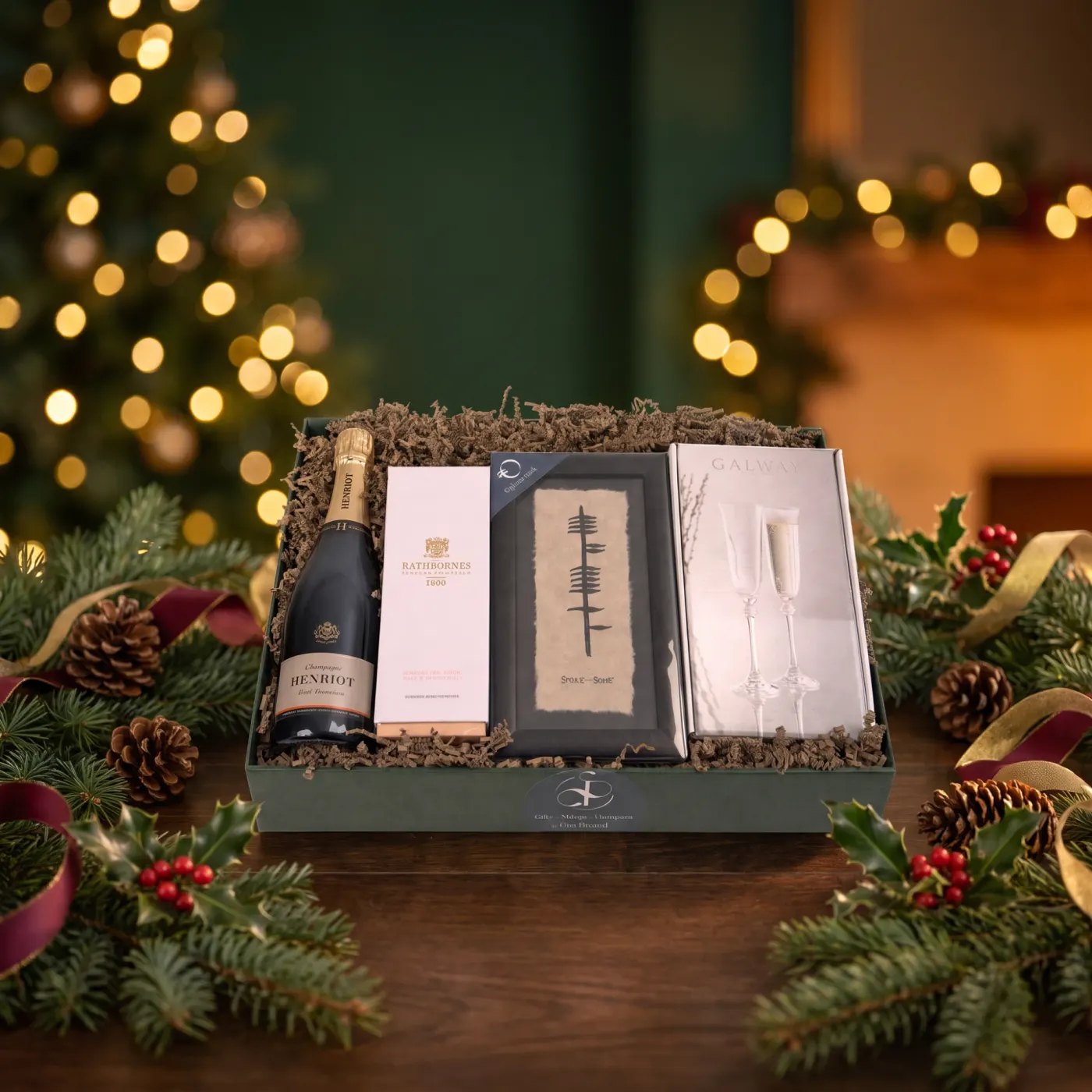 The New Home Luxury Hamper dressed for Christmas, a bottle of Henriot Champagne beside a Rathbornes candle, a framed ogham print and a boxed pair of Galway Crystal Champagne flutes